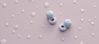 White LinkBuds on a pink background with water droplets