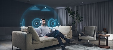 Man on a couch listening to headphones with an illustration of 360 Spatial Sound Personalizer effect around his head